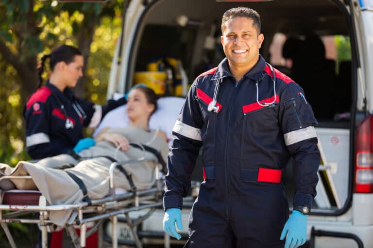 On-site medic standing beside a patient on a stretcher at an ambulance