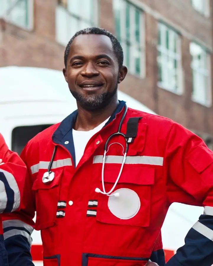 EMT in uniform standing in front of an ambulance