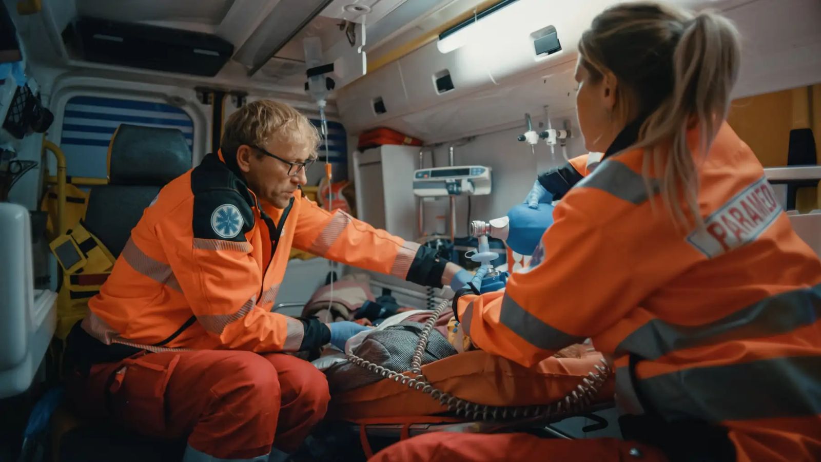 Two paramedics treating a patient in the back of an ambulance